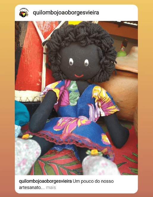 Boneca negra artesanal com um vestido colorido em azul, verde, amarelo e vermelho.